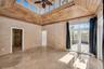 High-ceiling room featuring a wood-plank tray ceiling, clerestory windows, natural stone tile flooring, and French doors