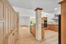Kitchen featuring custom wood cabinetry, stone-clad structural pillar, wood-finish flooring, built-in double oven, and stainless steel vent hood