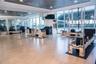 Expansive fitness studio featuring gleaming wood-finish flooring, floor-to-ceiling windows with natural light, modern ceiling-mounted lighting, and sp