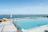 Expansive outdoor swimming pool with a surrounding tiled deck and glass perimeter railing