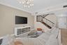 Contemporary lighting, crown molding, and wood-finish staircase with metal railings.