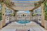 Outdoor spa with surrounding patterned paver patio, wood pergola with climbing vines.