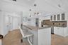 Kitchen featuring granite countertops, stainless steel appliances, white cabinetry with frosted glass, and pendant lighting.