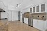 White cabinetry with frosted glass accents, stainless steel appliances, a built-in wine refrigerator, and tile flooring
