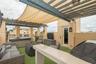 Rooftop terrace featuring a custom metal pergola with integrated shade canopy, built-in bar, artificial turf flooring, and a recessed spa