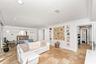 Large-format stone flooring, recessed ceiling lighting, wall-mounted floating shelves, and crown molding