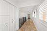 Hallway featuring stone tile flooring, white bi-fold closet doors, recessed lighting, plantation shutters, and a wrought-iron railing