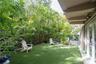 Private outdoor space featuring synthetic lawn, established tropical landscaping, and a covered patio