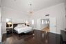 High-ceilinged room featuring dark wood-finish tile flooring, crown molding, multi-light metallic chandelier, and double doors opening to a secondary 