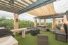 Rooftop terrace featuring a covered pergola, integrated overhead lighting, metal railings, and a built-in outdoor kitchen structure