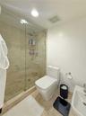 Walk-in shower featuring a frameless glass enclosure, stone tile surround, and a handheld shower fixture, complemented by natural stone flooring and a