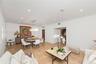 Open-concept area featuring stone tile flooring, crown molding, recessed lighting, and a rectangular multi-tiered crystal chandelier