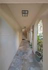 Covered walkway featuring a series of architectural arches, stone tile flooring, wall-mounted lantern-style lighting, and flush-mount overhead lightin