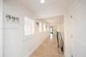 Hallway featuring stone tile flooring, plantation shutters, recessed lighting, and crown molding