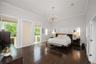 High ceilings with crown molding, wood-finish flooring, two glass-paneled exterior doors, and a decorative multi-bulb chandelier