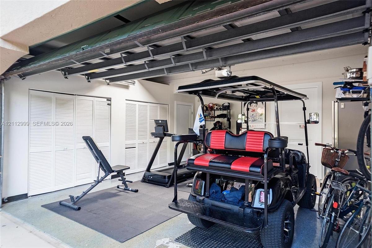 Garage featuring a dual-track ceiling-mounted door system and multiple sets of white louvered-door built-in storage closets