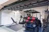 Garage featuring a dual-track ceiling-mounted door system and multiple sets of white louvered-door built-in storage closets