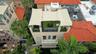 Rooftop terrace featuring synthetic turf, metal railings, and a tensile shade canopy, complemented by multiple lower-level balconies and terracotta ro