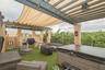 Rooftop terrace featuring a covered pergola with a retractable shade canopy, built-in outdoor kitchen, integrated lighting, and a composite-finish hot
