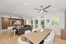 Living area featuring tile flooring, wood-finish wall paneling with integrated shelving, recessed lighting, ceiling fans, and arched windows with plan