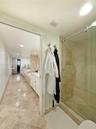 Bathroom featuring large-format tile flooring, a glass-enclosed shower with stone tile surround, and built-in cabinetry with a stone countertop