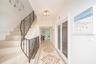 Foyer featuring stone stair treads, a decorative metal balustrade, intricate mosaic tile flooring inlay, and a flush-mount crystal chandelier