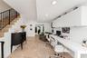 Stone-tiled flooring, built-in white desk with overhead cabinetry, and staircase featuring a black metal railing