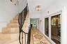 Foyer featuring stone tile flooring with decorative geometric inlay, a custom wrought-iron staircase railing, and a tiered crystal chandelier