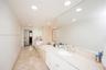 Bathroom featuring stone-finish flooring, a jetted soaking tub with a tiled surround, a lengthy stone-surface vanity with dual integrated sinks, and e