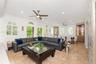Open-concept interior featuring large-format tile flooring, multiple arched windows with built-in shutters, dual ceiling fans, and integrated custom c