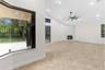 Spacious interior featuring tile flooring, vaulted ceilings with recessed lighting, a stone-surround fireplace, and large bay windows