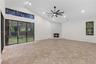 Vaulted ceilings featuring recessed lighting, expansive glass sliding doors, floor-to-ceiling stone-faced fireplace with a raised hearth, and neutral 