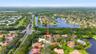 Aerial perspective of a multi-level residence featuring a clay tile roof, paved driveway, expansive lot with mature landscaping, and proximity to mult