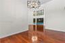 Two-story interior space featuring wood-finish flooring, high ceilings, geometric metal chandeliers, and oversized windows