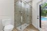Walk-in shower featuring a frameless glass enclosure, recessed wall niche, and textured multi-tonal tile surround, complemented by wood-finish floorin