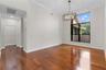 High-ceiling room featuring wood-finish flooring, a contemporary multi-arm metal chandelier, crown molding, and a large multi-pane window