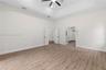 Interior room featuring a high tray ceiling, wood-finish flooring, a ceiling fan with integrated lighting, French doors, and multi-panel interior door