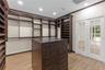 Custom storage cabinetry featuring extensive shelving, a central island with integrated drawers, wood-finish flooring, recessed lighting, and white Fr