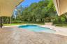 Covered patio featuring stone tile flooring, in-ground swimming pool with built-in spa, and a poolside pergola with an integrated bar