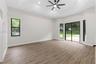 Tray ceiling with integrated recessed lighting, wood-finish flooring, black-framed windows, and sliding glass doors with exterior access