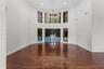 Expansive room featuring high ceilings, wood-finish flooring, floor-to-ceiling windows, a multi-tier circular chandelier, and sliding glass doors