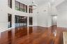 Double-height ceilings featuring floor-to-ceiling windows, wood-finish flooring, a large circular iron chandelier, and recessed lighting