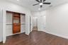 Wood-finish flooring, closet with built-in wooden cabinetry, multi-panel doors, and a ceiling fan with integrated lighting