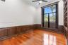 Wood-finish flooring, custom dark wood wall paneling, full-height built-in shelving, floor-to-ceiling windows, and crown molding