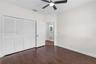 Wood-finish flooring, multi-panel louvered closet doors, and ceiling fan with integrated lighting
