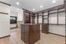 Custom dark wood cabinetry featuring floor-to-ceiling shelving, hanging rods, and a center island with built-in drawers