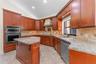 Kitchen featuring wood cabinetry, stone countertops, tiled backsplash, built-in double wall oven, and a center island