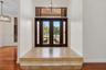 Entryway featuring double glass-paneled doors, decorative tile inlay, stepped tile flooring, transom window, and multi-arm chandelier