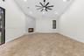 High vaulted ceilings, tile flooring, stone-accented corner fireplace, multi-blade ceiling fan, and large-format sliding glass doors