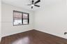 Interior room featuring dark-tone wood-finish flooring, a contemporary matte black ceiling fan with an integrated light, and a single window with hori